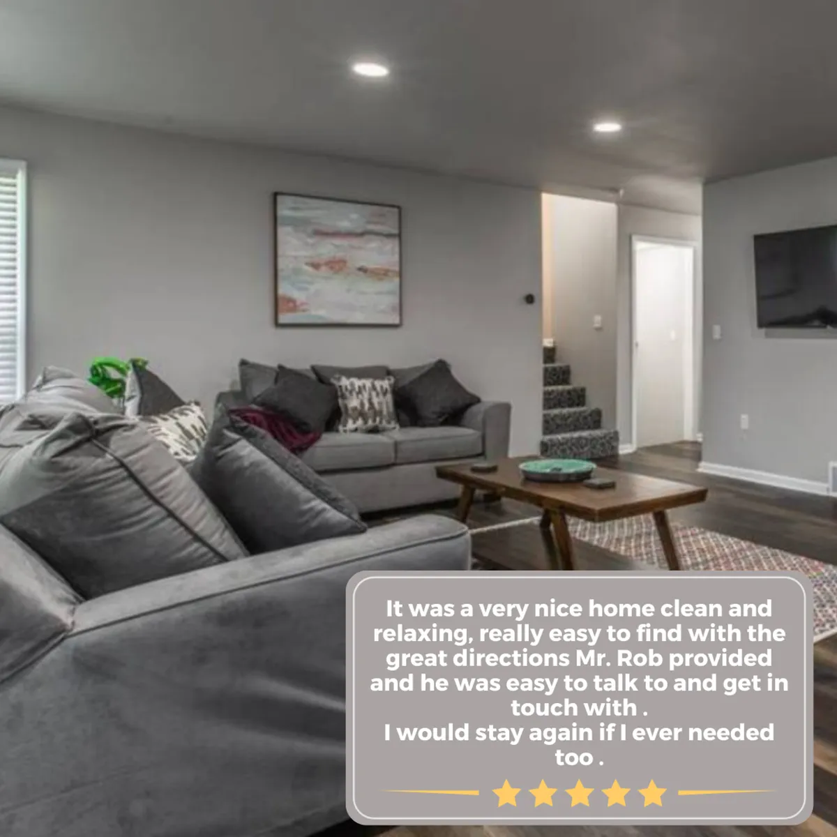 This interior image features a comfortable gray sofa, a wooden coffee table, and decorative wall art, creating a warm and cozy atmosphere. The space is ideal for groups relaxing or socializing before or after sporting events.
