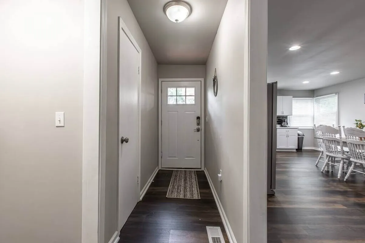 This image captures the home's front door and hallway, featuring a welcoming rug and softly hued walls. The scene evokes a sense of arrival and transition, inviting guests to step inside from their local adventures.